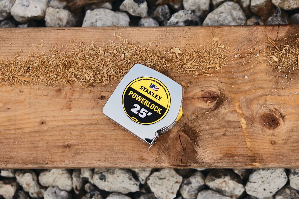 STANLEY 33-425 tape measure on wood plank with sawdust, exterior view.