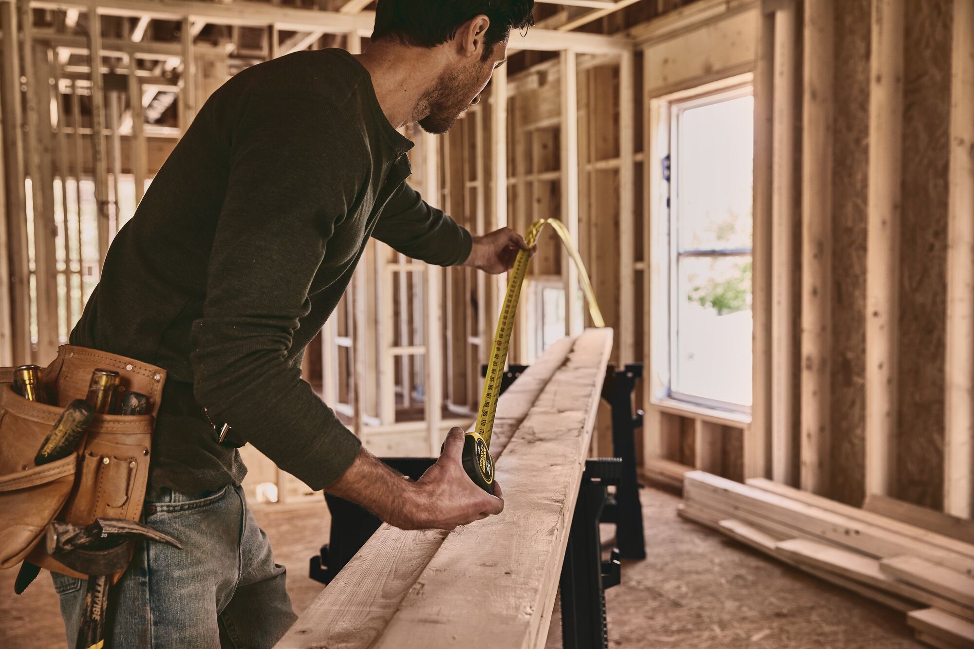 STANLEY 33-725 tape measure used to measure wooden plank in construction site, side angle photography.