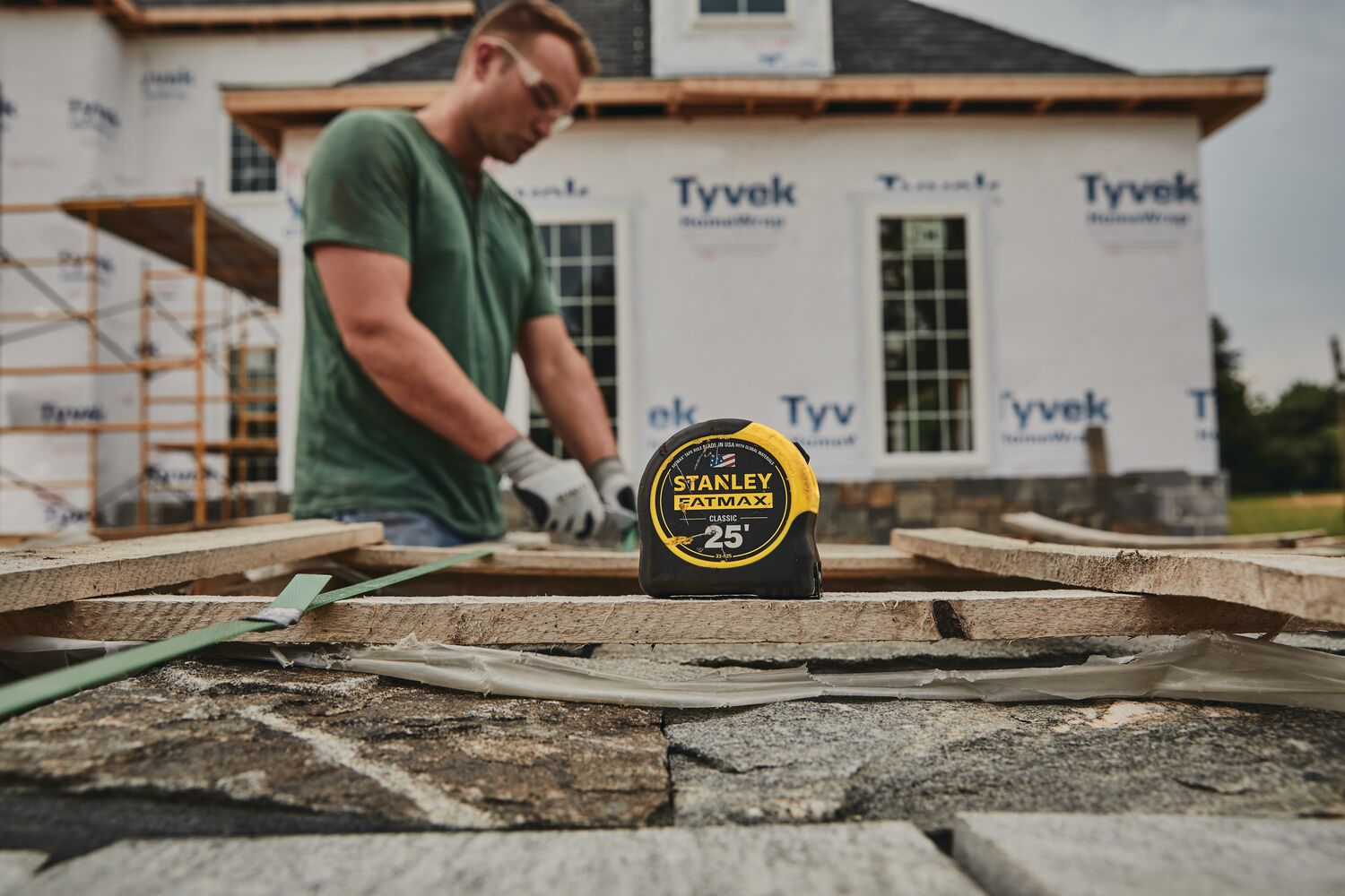 STANLEY 33-725 tape measure on stone surface at construction site, home under renovation in background.
