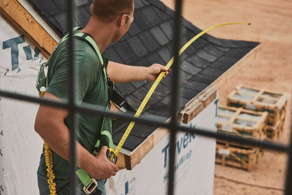 STANLEY 33-735 tape measure used by a worker measuring a roof edge at a construction site, side angle.