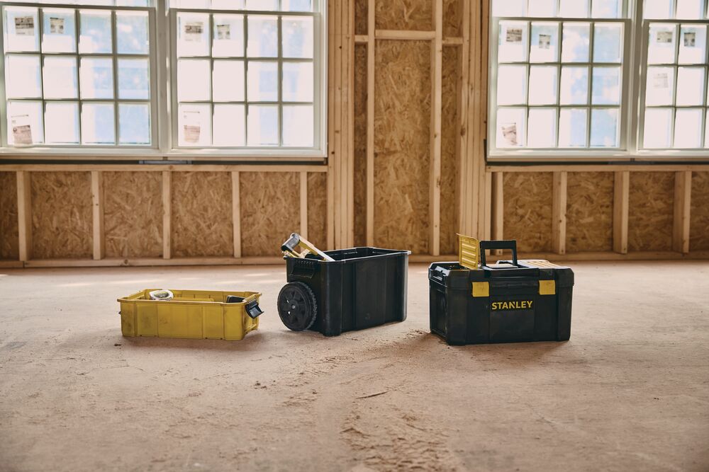 STANLEY STST18631 toolbox set with three black and yellow toolboxes, shown on a construction site floor.